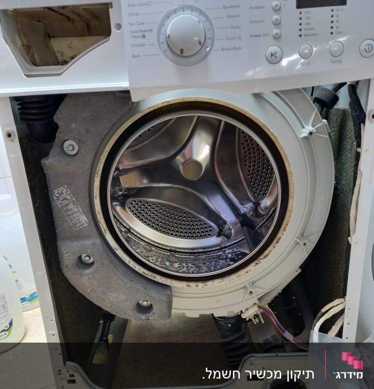 מכונת כביסה פתוחה עם תוף חשוף וחוטי חשמל